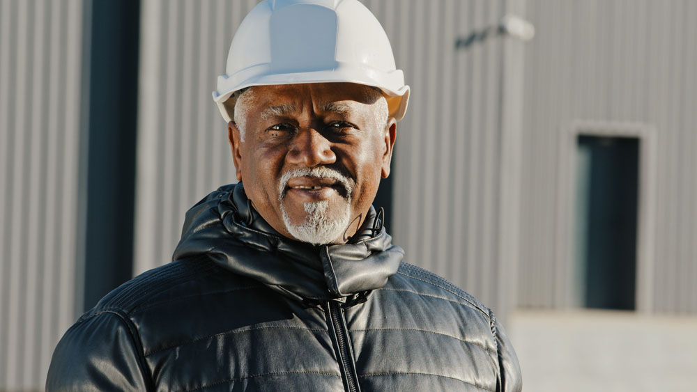 Portrait d'un homme âgé, afro-américain, confiant, ingénieur professionnel, travailleur de la construction avec un casque de sécurité, entrepreneur, contremaître, debout à l'extérieur, sur un site, en gros plan, regardant l'appareil photo.