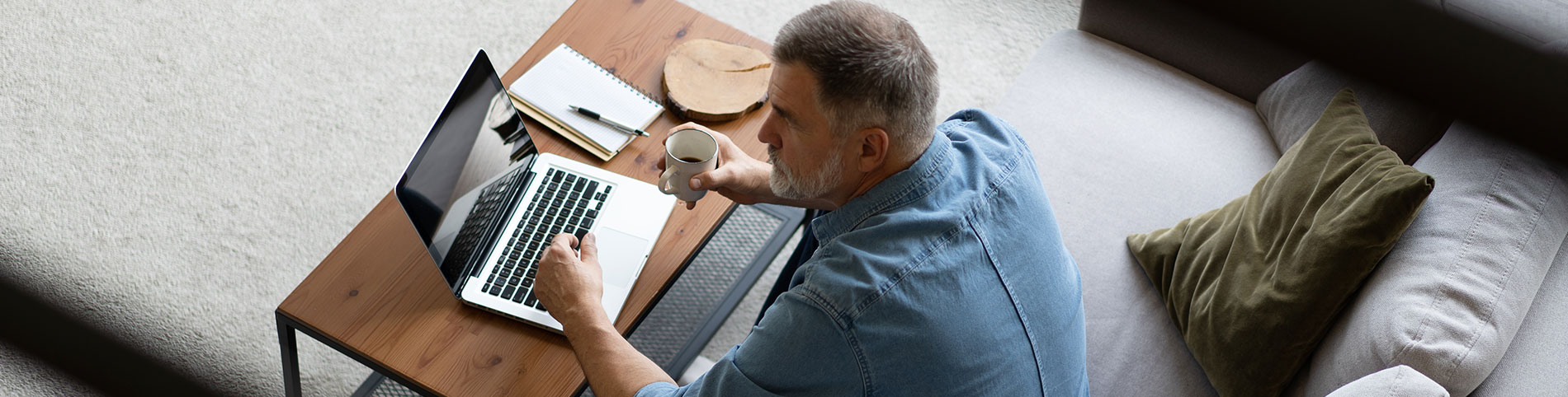 Retraité sur son ordinateur lisant des médias un café à la main